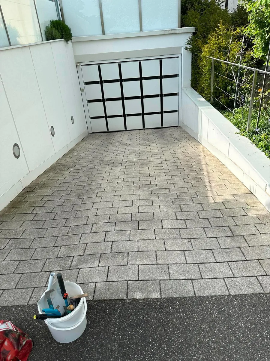 Heller, frisch gereinigter Pflasterhof mit Garagentor – echtes Einsatzfoto